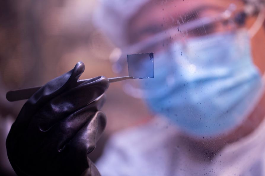 Yongxi Li sostiene una muestra de una célula solar transparente